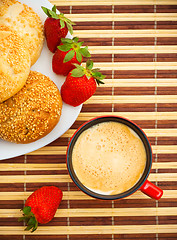 Image showing coffee, buns and strawberries on table