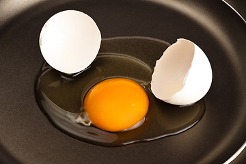 Image showing broken egg on black pan