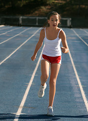 Image showing Girl exercising on a blue racetrack