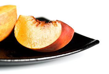 Image showing red peaches slices on black dish
