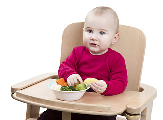 Image showing young child eating in high chair