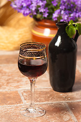 Image showing Black jug for wine and a glass of red wine 