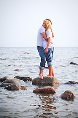 Image showing couple embrace on a stone in sea