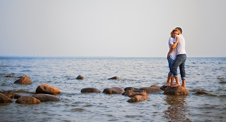 Image showing couple embrace on a stone in sea
