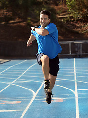 Image showing Man running  on a blue racetrack