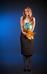 Image showing pretty teacher with globe and maple leaves