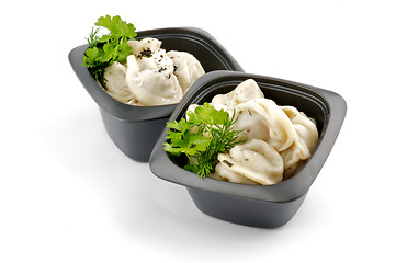 Image showing Meat pelmeni with sour cream and greens in black bowls