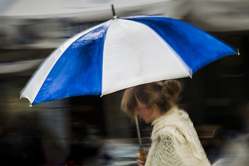 Image showing Woman under blue striped umbrella