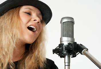 Image showing Young woman singing with studio microphone