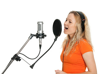 Image showing Girl in orange t-shirt singing with studio microphone