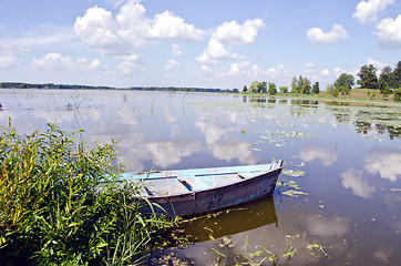 Image showing Spring lake fragment. Old boat moored on shore. 