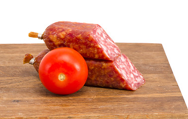 Image showing cut smoked sausage pieces and tomato cutting board 