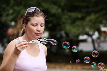 Image showing Yung woman blows bubbles
