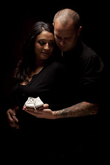 Image showing Mixed Race Couple Holding New White Baby Shoes on Black