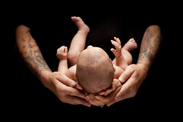 Image showing Hands of Father and Mother Hold Newborn Baby on Black