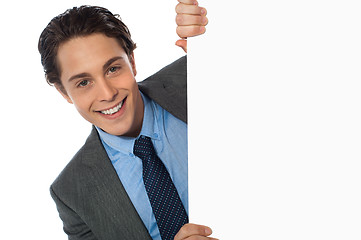 Image showing Businessman peeking behind a whiteboard