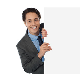 Image showing Businessman peeping from behind the blank board