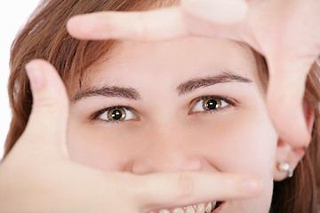 Image showing Pretty adult woman looking through a frame made by her hands.