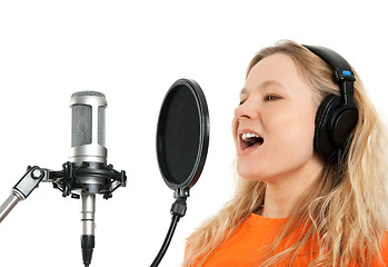 Image showing Girl in headphones singing with studio microphone
