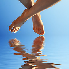 Image showing female and male foot in blue water  