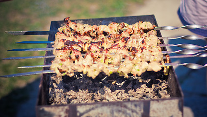 Image showing shish kebab in process of cooking on open fire outdoors