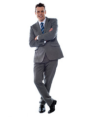 Image showing Cheerful young businessman leans against wall