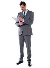 Image showing Successful businessman writing notes on clipboard