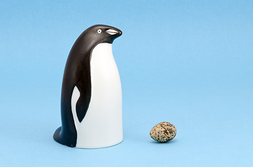 Image showing penguin bird sculpture and egg isolated on blue 