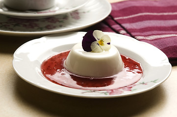 Image showing Vanilla panna cotta with berry sauce and spring flower