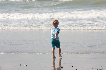 Image showing young child walking on the sand to the waves