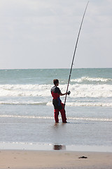 Image showing fisherman casting until the fish on a sandy beach