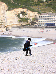 Image showing a young child dressed as a fisherman plays on the beach