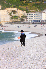 Image showing a young child dressed as a fisherman plays on the beach