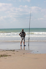 Image showing fisherman casting until the fish on a sandy beach