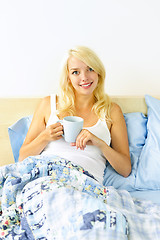 Image showing Pretty woman sitting in bed with coffee cup