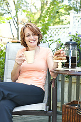 Image showing Woman in backyard with coffee and cookies