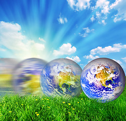 Image showing Earth globe rolling on green grass