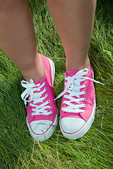 Image showing Pink sneakers on girl legs on grass