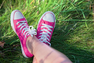 Image showing Pink sneakers on girl legs on grass