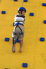 Image showing A child abseilling down a climbing wall