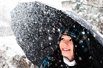 Image showing Young woman with umbrella in a blizzard