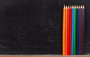Image showing Colorful pencils against chalk board