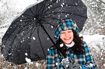 Image showing Young woman with umbrella in a blizzard