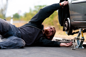 Image showing Handsome young man repairing car