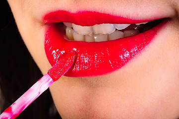 Image showing Girl putting on red lipstick