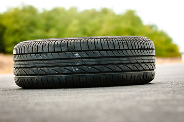 Image showing Abandoned car tyre on the road with green background
