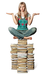 Image showing woman in lotus pose balancing on pile of books