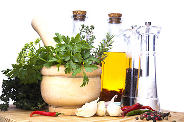 Image showing Mortar and pestle with fresh herbs, spices, virgin olive oil, sa