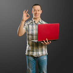 Image showing asian male with laptop in his hands shows OK