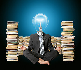 Image showing businessman in lotus pose and lamp-head with many books near